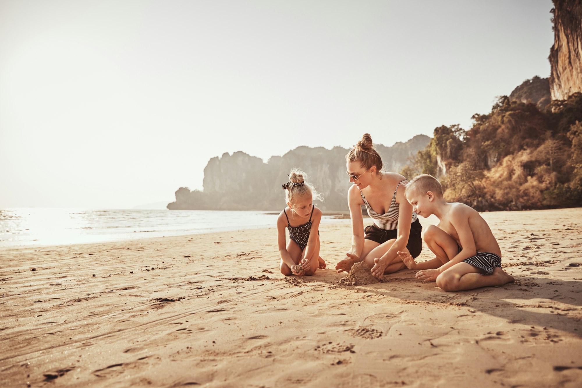 Mother and kids playing in the sand at the beach